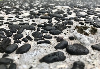Closeup picture of a pathway  made with black lava stone pebbles, pictured from the beach in Moroni...