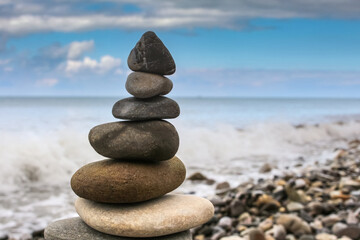 harmony tower made of sea pebbles on the beach against the blue sky