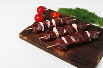 Raw beef liver kebab on skewers on wooden board