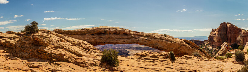 Fototapeta na wymiar Panorama shot of Mesa arch and look through to canyons at sunny day in canyonlands in utah, america