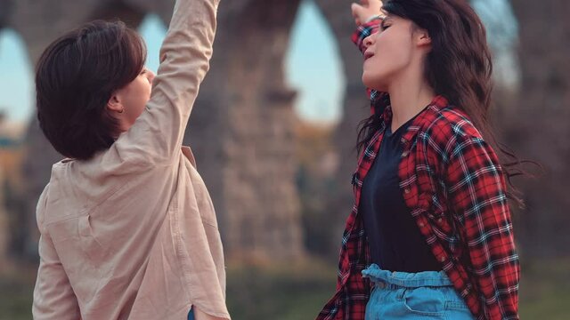 youth, fun - two young women have fun singing and dancing at the park
