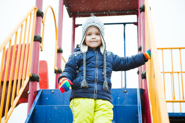 Cute little boy in winter clothes on the Playground.