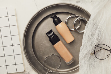 Tray with bottles of makeup foundation and accessories on light background