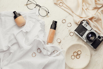 Bottles of makeup foundation, accessories and photo camera on light background