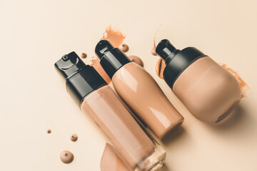 Bottles of makeup foundation and samples on color background