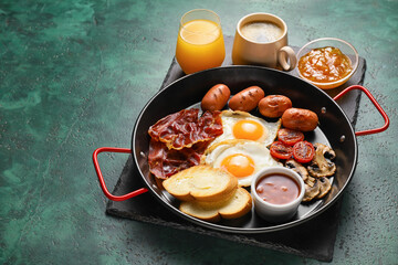 Traditional English breakfast with fried eggs in pan on color background