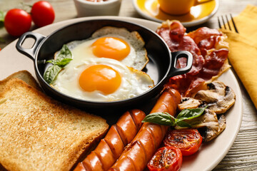 Traditional English breakfast with fried eggs on wooden background