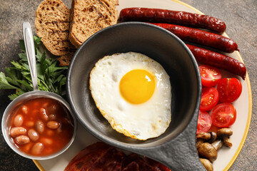 Traditional English breakfast with fried eggs in plate on grunge background