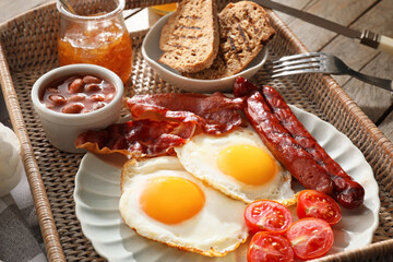 Traditional English breakfast with fried eggs in tray on wooden background