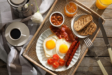 Traditional English breakfast with fried eggs in tray on wooden background