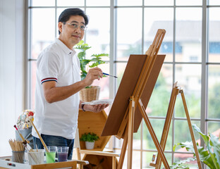 Naklejka premium Senior man and woman couple, husband and wife, painting image together in home gallery with warm and happy circumstance. Idea for time-sharing and relaxing for older people after retirement