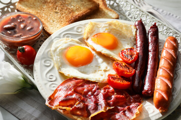 Traditional English breakfast with fried eggs in tray on light background
