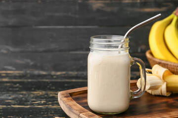 Mason jar with tasty banana smoothie on wooden background