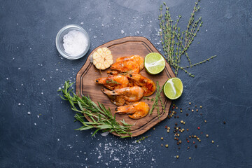 Board with tasty shrimps on dark background