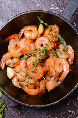 Frying pan with tasty shrimps on dark background