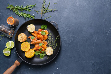 Frying pan with tasty shrimps on dark background