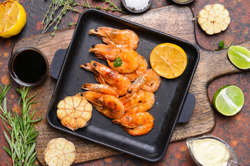 Pan with tasty shrimps on grunge background