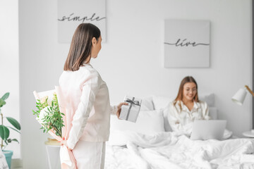 Young woman greeting her girlfriend in bedroom at home