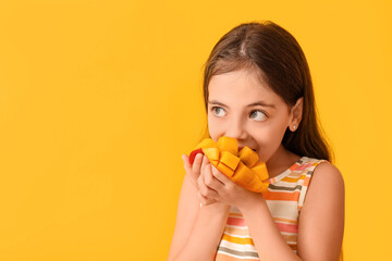 Cute little girl eating tasty mango on color background