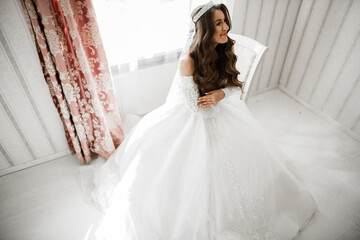 Fototapeta premium Beautiful bride wearing fashion wedding dress with feathers with luxury delight make-up and hairstyle, studio indoor photo shoot