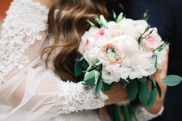 Beautiful young wedding couple posing with bouquet of flowers in hands