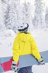 Woman snowboarder in bright suit in a sports helmet holds a snowboard. Extreme sports. Leisure....