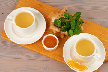 Cup of tea with ginger and mint on wooden table