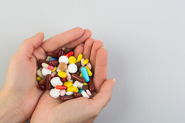 Many pills and capsules of different colors in the palms of a woman on a gray background,Health care concept,COVID-19; Coronavirus; Treatment; Virus; Copy Space