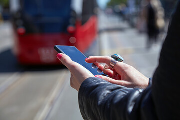 Woman using cellphone on a tram station in Europe.