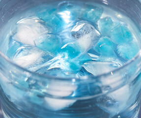 blue ice cubes in a glass of water