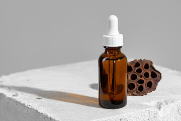 Glass jar of skincare serum on concrete block