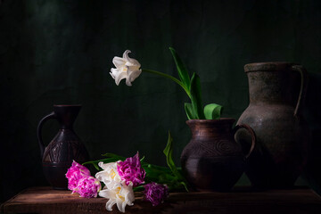 Naklejka na ściany i meble Classic still life with beautiful white tulip flower in vintage clay jar and cut white and pink tulips bouquet lying on the table. Art photography.