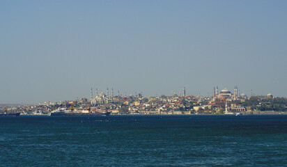 A panoramic shot of a scenery that captures a sea near a path full of buildings and mosque under the sky. This view is from Istanbul, Turkey.