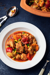 Chicken stew with potatoes, paprika, peas and corn on a white plate. Slow Cooked Chicken stew in a ceramic bowl. Top view.