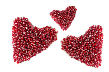 Three hearts from pomegranate seeds on a white background.