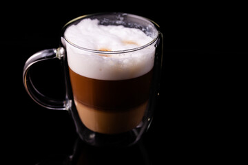 Cappuccino coffee in a transparent cup close-up.
