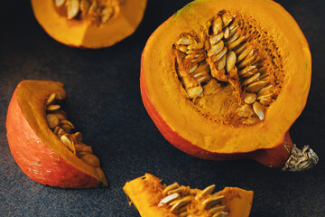 Pumpkin slices with seeds on darl background. Top view