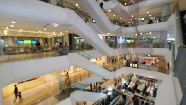 Blurred and unrecognizable crowded people are walking in shopping mall. Escalators in modern shopping mall.