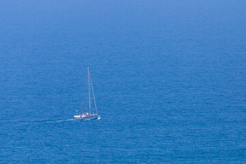 Obraz premium White sail boat on blue water of sea. Minimal composition with copyspace