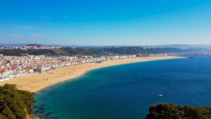 Bird's-eye view on Nazare beach riviera on the coast of Atlantic ocean with Nazare town. Portugal