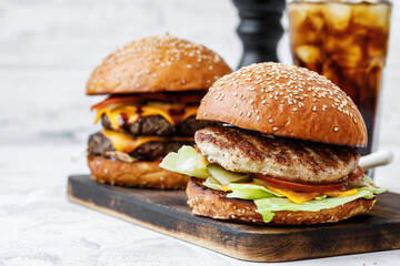 Freshly cooked burger on wooden board on light background