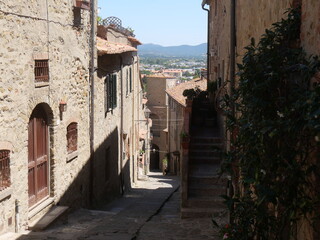 Typical medieval street of Castiglione della Pescaia, squeezed between the houses covered with flowers and vegetation.