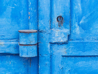 Metal door with weathered blue paint and security insert lock.