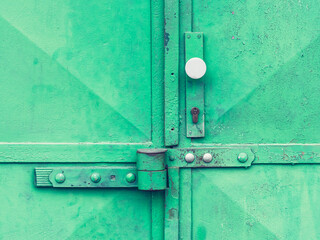 Locked green warehouse metal door. Detail view to locked latch