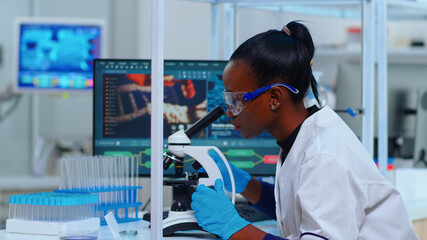 African woman biochemist using microscope in modern equipped laboratory. Black scientist doctor...