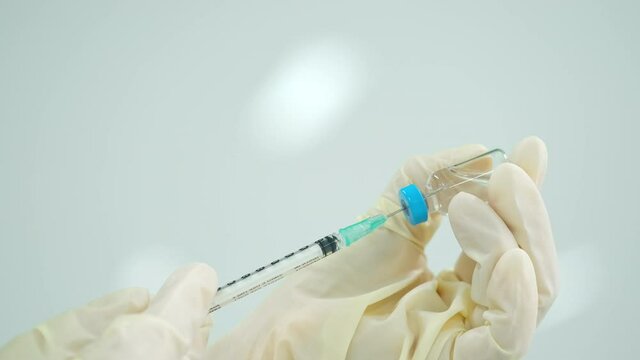 Close up of the syringe is inserted into the vaccine vial. Scientist or doctor hand holding COVID vaccine vial. Coronavirus immunization flu treatment vaccination concept. Health and medical concept