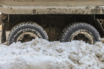 Large wheels of a truck are covered with snow