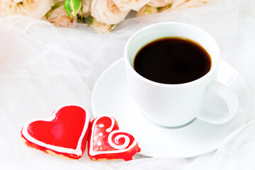 Valentine's day. Wedding . A Cup of coffee and two gingerbread heart on a background of roses.