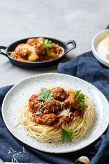 The homemade italian pasta or spaghetti with meatball , cheese and tomato sauce placed in a white dish with on dark blue tablecloth on the table..