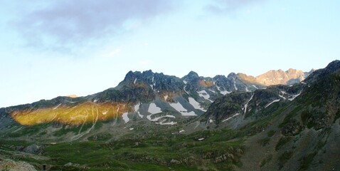 A panoramic shot of a mountain which has snows and a sunlight that spreads through the end of the mountain